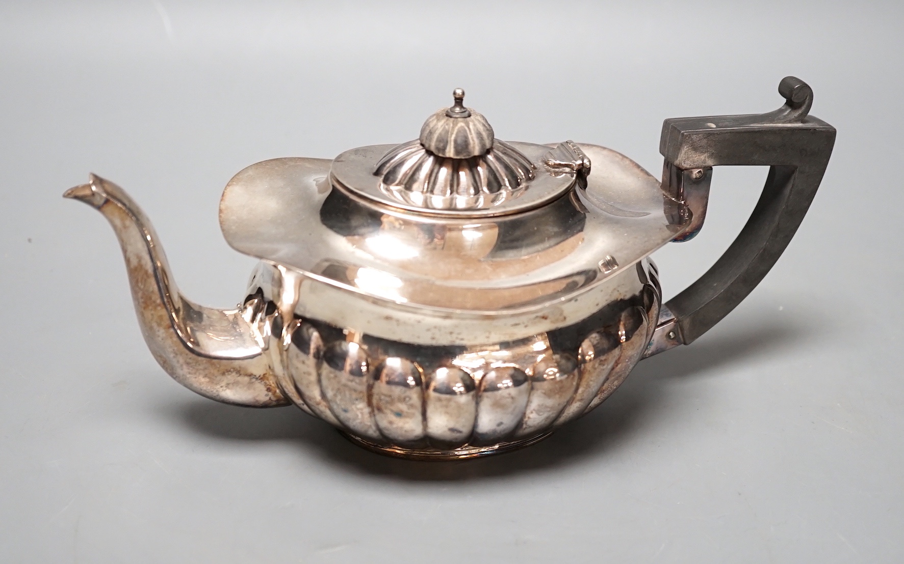 A late Victorian demi-fluted silver teapot, Chester, 1898, gross 10oz.